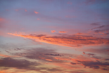 Beautiful evening blue sky at sunset with flaming bright light clouds. A warm summer evening at sunset.