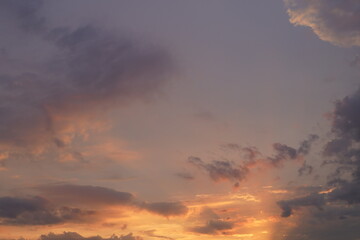 Beautiful evening blue sky at sunset with flaming bright light clouds. A warm summer evening at sunset.