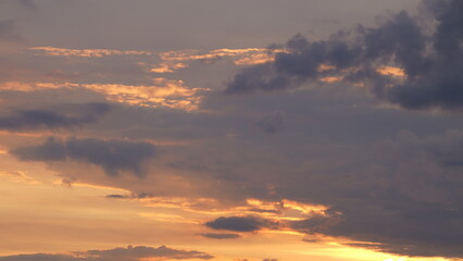 Beautiful evening blue sky at sunset with flaming bright light clouds. A warm summer evening at sunset.