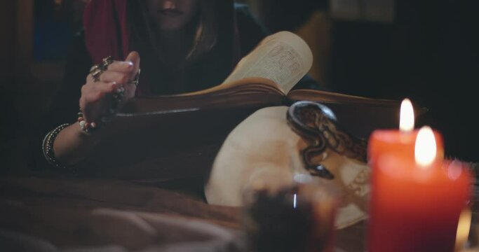 Young dark witch reading magic book looking for spell