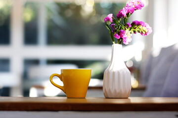 Coffee cup and white vase, flowers placed on the wooden table