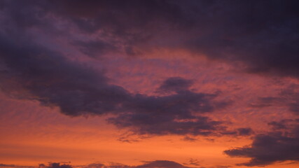 Beautiful evening blue sky at sunset with flaming bright light clouds. A warm summer evening at sunset.