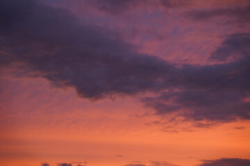 Beautiful evening blue sky at sunset with flaming bright light clouds. A warm summer evening at sunset.