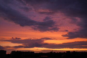 Beautiful evening blue sky at sunset with flaming bright light clouds. A warm summer evening at sunset.