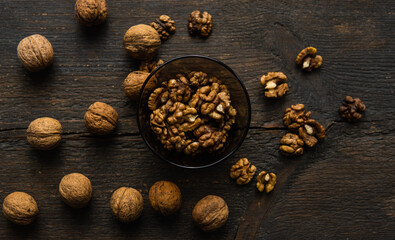 Walnut in a smale plate with scattered shelled nuts and whole nut which standing on a wooden vintage table. Walnuts is a healthy vegetarian protein nutritious food. Walnut on rustic old wood.