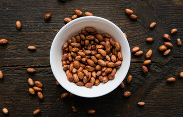 Peanut nuts in a small plate on a vintage wooden table. Peanuts nut is a healthy vegetarian protein nutritious food.