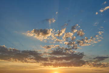 Beautiful evening blue sky at sunset with flaming bright light clouds. A warm summer evening at sunset.
