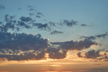 Beautiful evening blue sky at sunset with flaming bright light clouds. A warm summer evening at sunset.