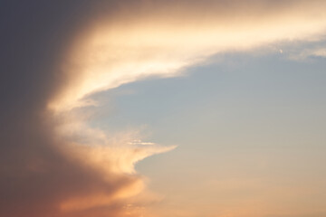 Beautiful evening blue sky at sunset with flaming bright light clouds. A warm summer evening at sunset.