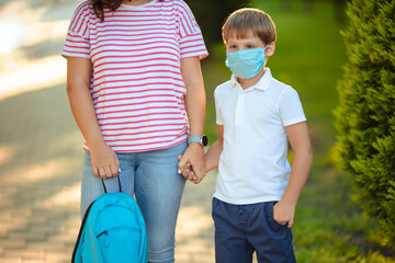 Fototapeta na wymiar mom and son schoolboy in medical masks on the way to school