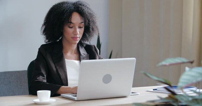 Front view of serious focused female entrepreneur or pretty professional business woman writer sitting at office desk, using laptop for typing. write email, study and surf in internet