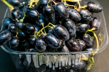 Seedless dark blue grapes in plastic package; grapes are a type of fruit growing in clusters and can be variously crimson, black, dark blue, yellow, green, orange, and pink. Nice fruit for health