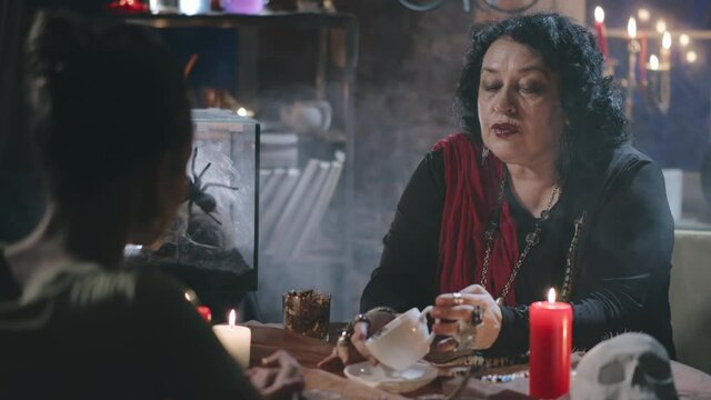 Gypsy witch predicting future of client reading holding coffee cup