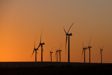 A wind farm during sunset. Turbines generating electricity. Green energy