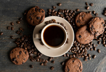 Coffee cup with cookies on wooden table background. Mug of black coffee with scattered coffee beans and cookies on a wooden table. Fresh coffee beans.