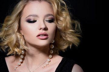 Gorgeous blonde, portrait on a black background. Beautiful young girl, makeup for the celebration.