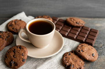 Coffee cup with cookies and chocolate on wooden table background. Mug of black coffee with...
