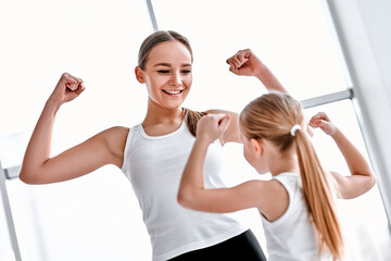 Mother and daughter showing strong hands in gym