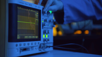 Close up of hand turning dial of modern electronic oscilloscope