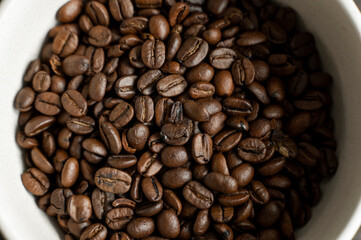 Bowl filled of fresh arabica or robusta coffee beans on a wooden table.
