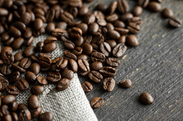 Coffee beans on a linen textile and on a wooden table background. Fresh arabica coffee beans.