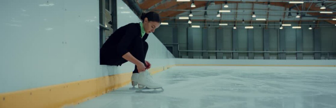 Professional Teenager Boy Figure Skater Tying Laces On Skates Before Training On Indoor Ice Arena. Shot On RED Cinema Camera With 2x Anamorphic Lens, 75 FPS Slow Motion