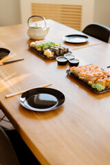 Close up of mix of sushi rolls on a table at home. Waiting friends to eat sushi rolls together using bamboo sticks.