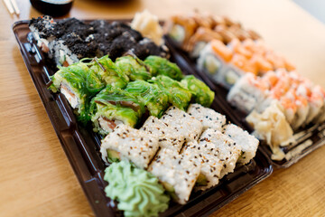 Sushi Roll Delivery. Salmon, avocado, cream cheese Philadelphia, caviar tobica, sea cabbage, shrimps on wood background. Sushi menu. Japanese food.