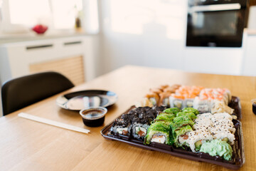 Close up of mix of sushi rolls on a table at home. Waiting friends to eat sushi rolls together using bamboo sticks.