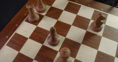 Top view of chess board with white wooden figures during game