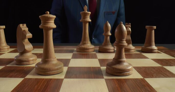 Close up of man making move with white bishop on chessboard during chess game