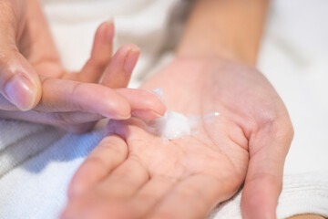 Fototapeta na wymiar Closeup woman applying moisturizing cream/lotion on hands, beauty concept..