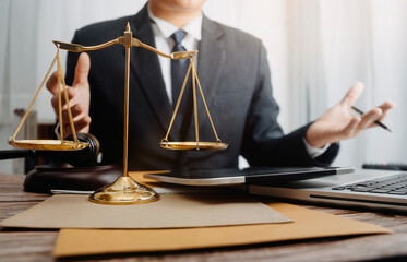 Justice and law concept.Male judge in a courtroom with the gavel, working with, computer and docking keyboard, eyeglasses, on table in morning light