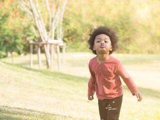 Cute little mix race African boy making funny face while playing in the park.