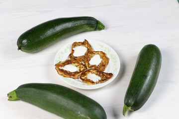 Fritters of Green zucchini marrows on white plate on wooden background