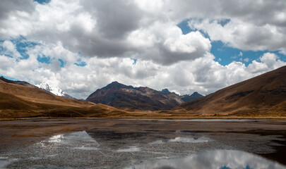 Panorama of mountain and lake landscape with ice and snow and cloudy blue sky, teal and orange, in Huaraz, Peru