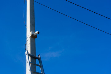 Surveillance camera on a pole against a blue sky.