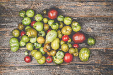 Heap of different sorts of tomatoes on a wooden table