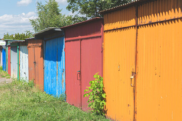 Row of colorful rusty garages or outdoor storage sheds. Old garage door closed with latch, padlock or hasp