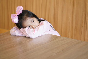 Asian child cute or kid girl vacant sleep or absent-minded for relax on table in classroom at nursery school because sadly and depressed or repressed to lonely and waiting mother with bored at home