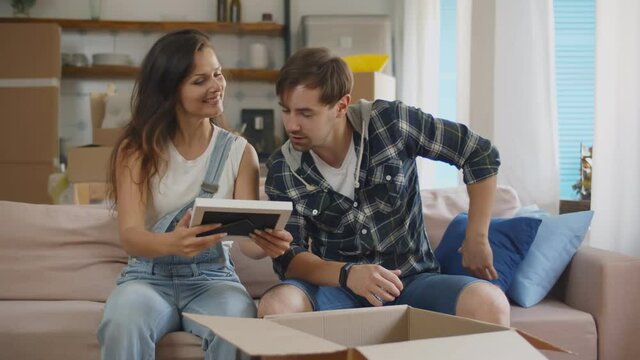 Happy young couple packing belonging in cardboard boxes