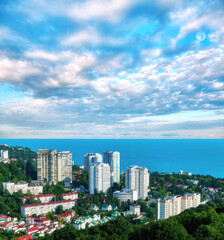 Aerial view of blue coast of Black Sea near  Sochi city with residential houses and recreation area under summer cloudy sky