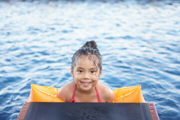 Asian child cute or kid girl smiling swim and wear swimming armband or life jacket with vacation...