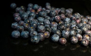 Blueberries scattered on a dark background. Blurred view