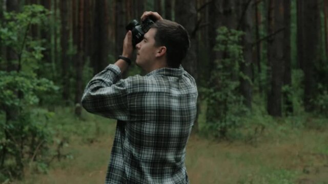 Male photographer is taking photographs in a forest