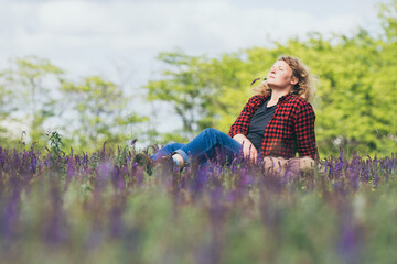 Woman relaxing among wild salvia flower field