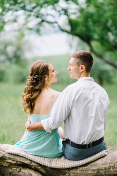 happy guy in a white shirt and a girl in a turquoise dress are walking in the forest park