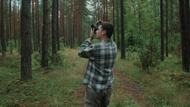 Male photographer is taking photographs in a forest