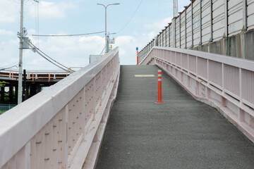 川を越える登り坂の歩道の真ん中に設置されたセンターポール・横構図