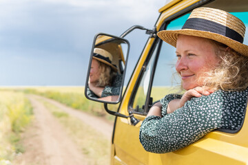 Young blonde woman travelling by campervan though the countryside